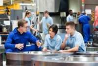 Three factory workers in workspace talking.