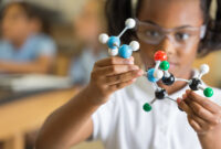 Elementary science student using plastic atom model educational toy
