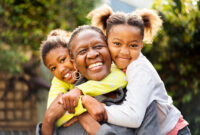 Senior woman cuddling her two granddaughters outdoors