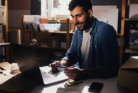 Cheerful man holding a credit card and using a laptop computer for online shopping