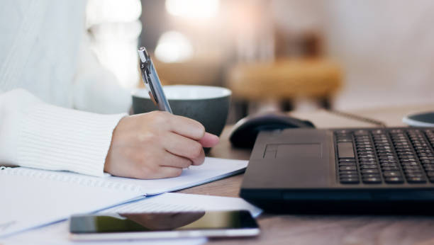Cropped shot of hand Young female using laptop working at home and writing her plan on paper, Concept work from home